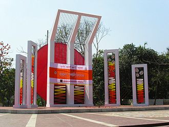 Image représentant un monument en béton et métal, contenant le cercle rouge du drapeau du Bangladesh