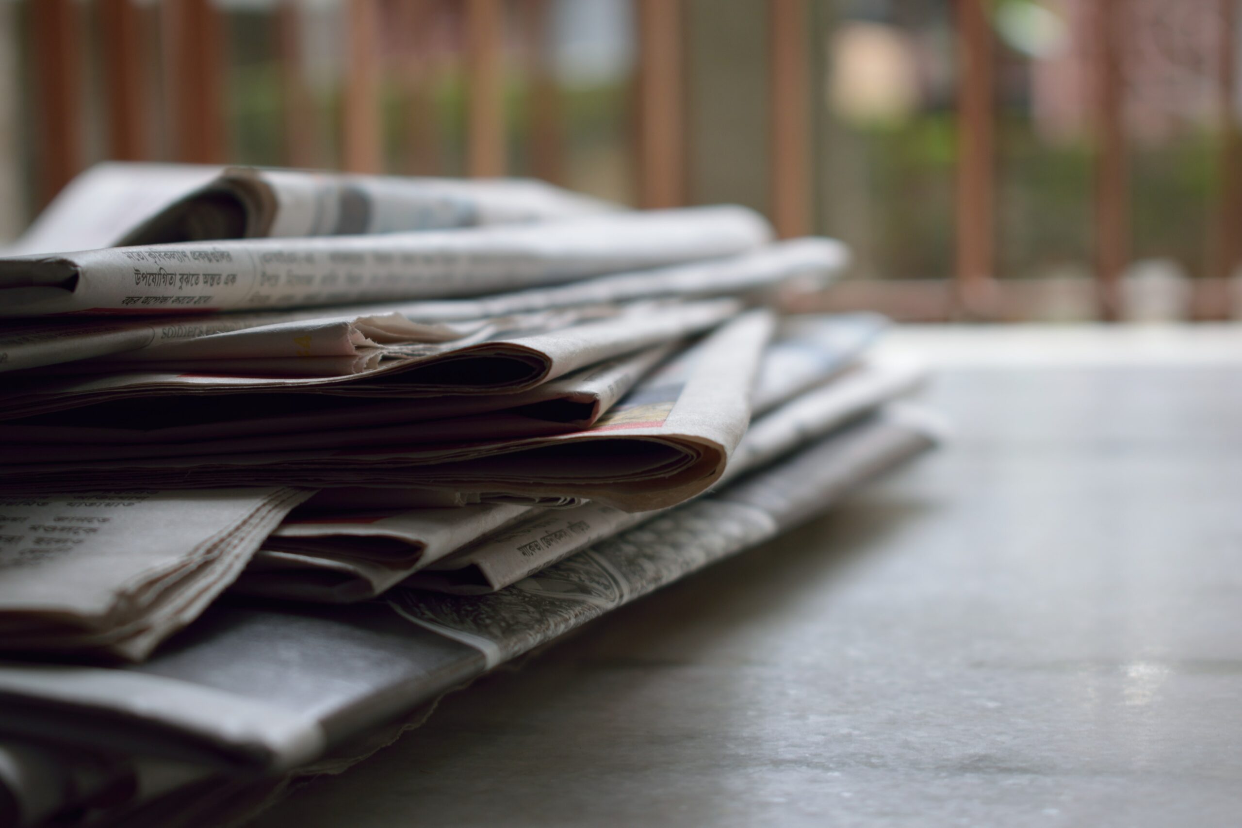 Actualités positives : pile de journaux posés sur une table en bois.