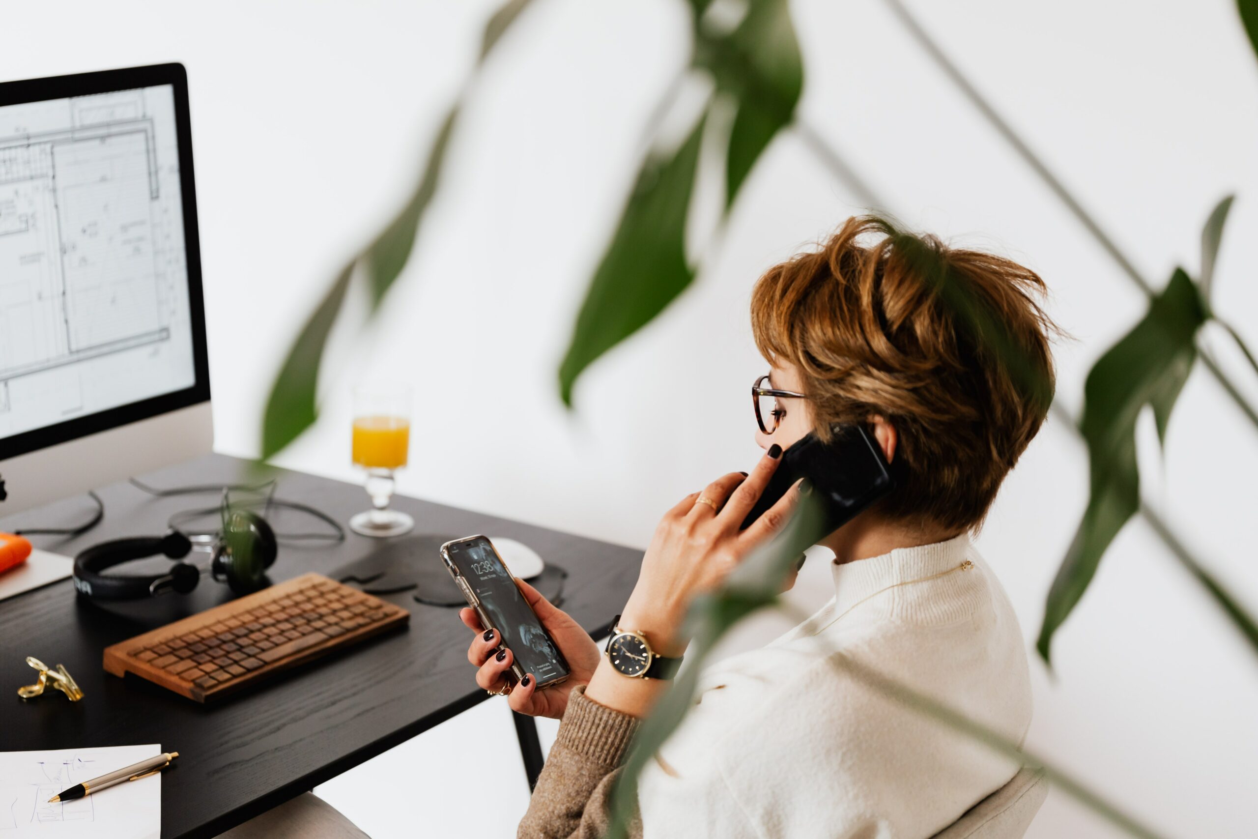 image représentant une personne au téléphone assise à son bureau devant son ordinateur.